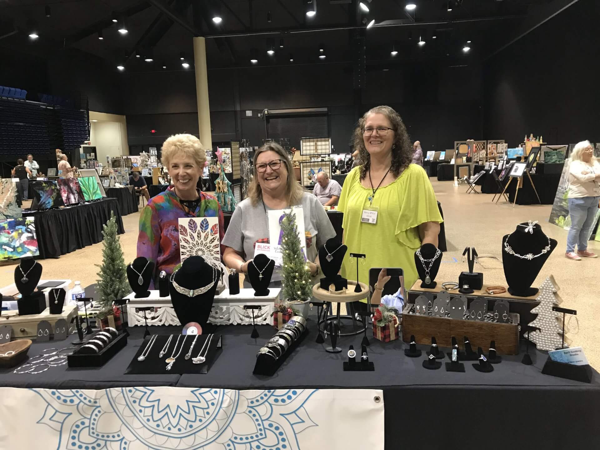 a group of women standing in front of a table with jewelry