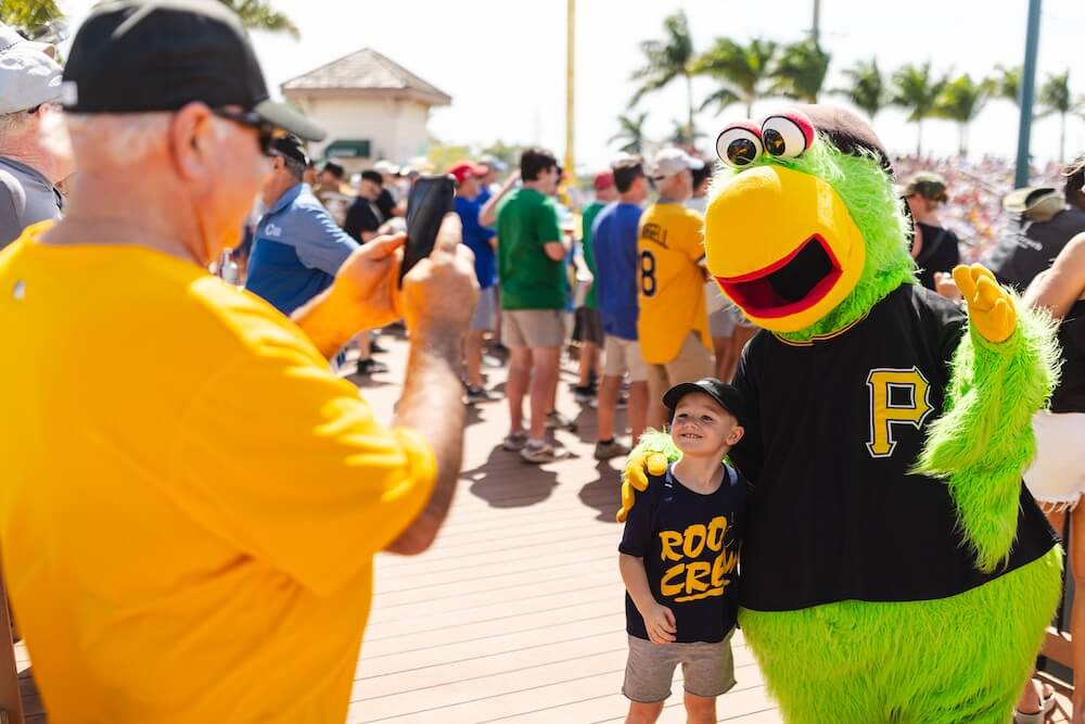 a man taking a picture of the Pittsburgh Pirates Parrot mascot and his child