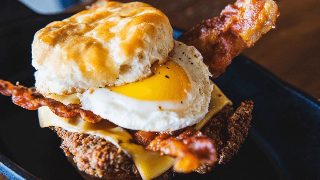 a bacon and egg and fried chicken sandwich on a plate