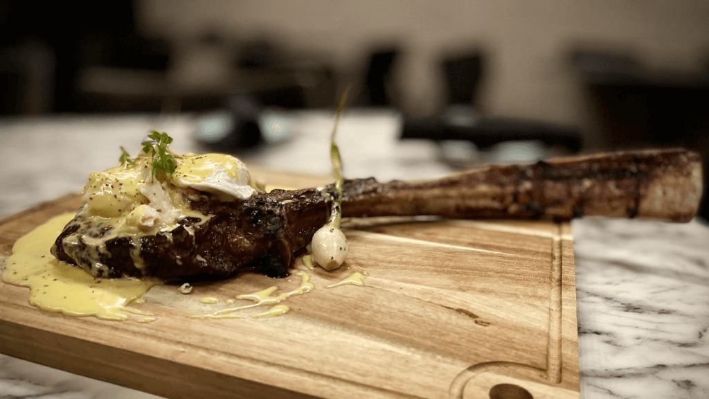 a tomahawk steak with an egg on a wooden board