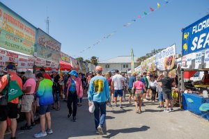 a crowd of people walking in in a street festival selling seafood