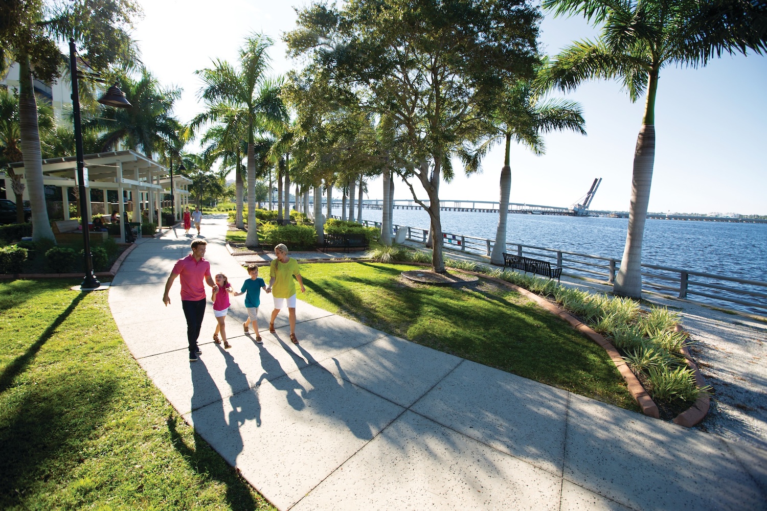 family of four strolling the bradenton riverwalk by the manatee river on a sunny day