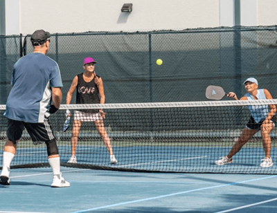 three people playing pickleball outdoors at The Center of Anna Maria Island